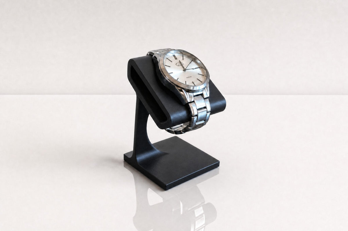 TatraHold Solitaire in Graphite holding a steel watch, warm natural light